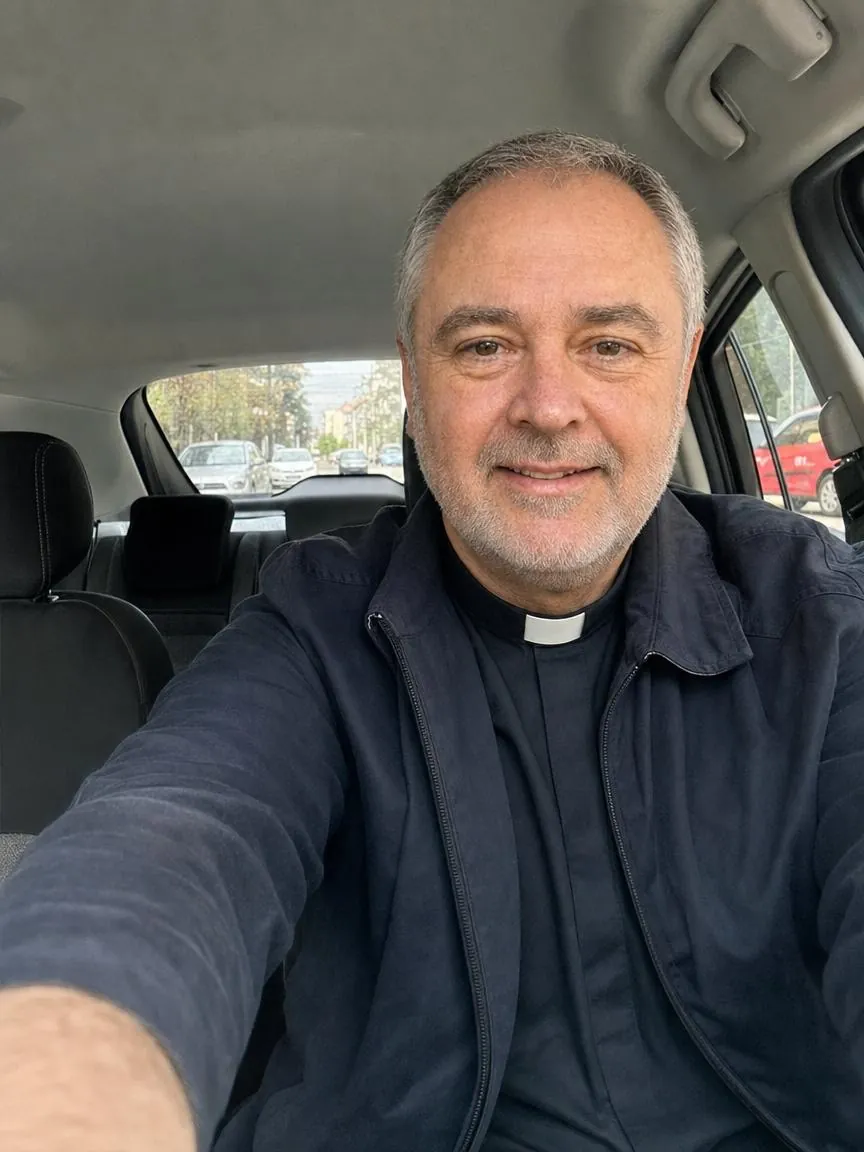 A phone selfie of Fr. Marco in the driver's seat of his car