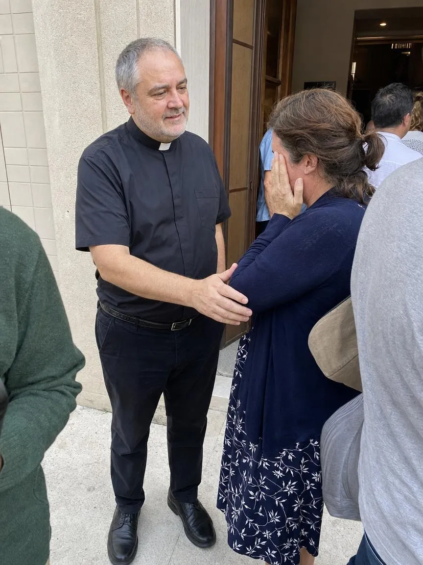 Fr. Marco with his hand on a woman's arm outside a church door after a service