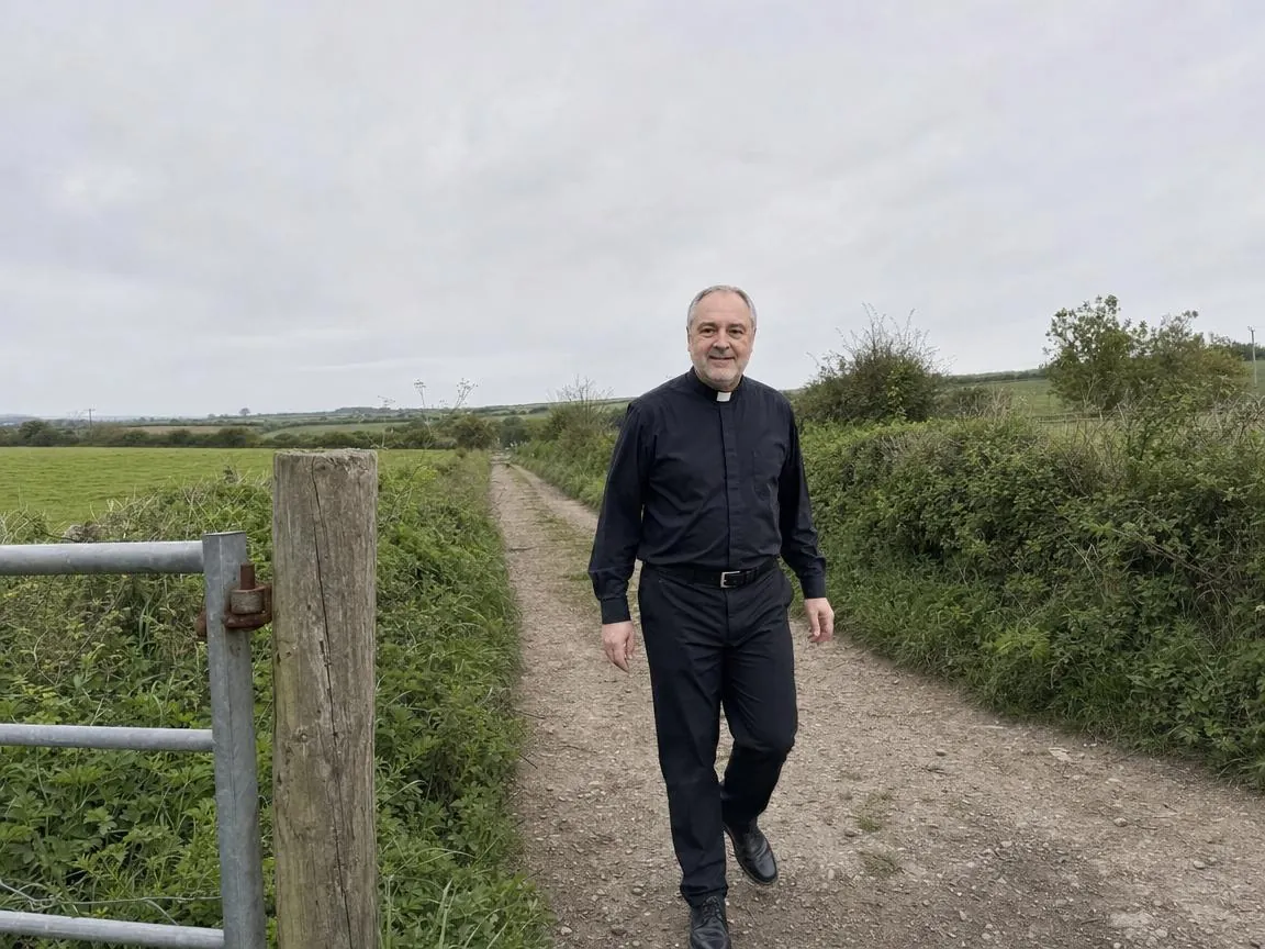 Fr. Marco walking a track across open countryside under a grey sky