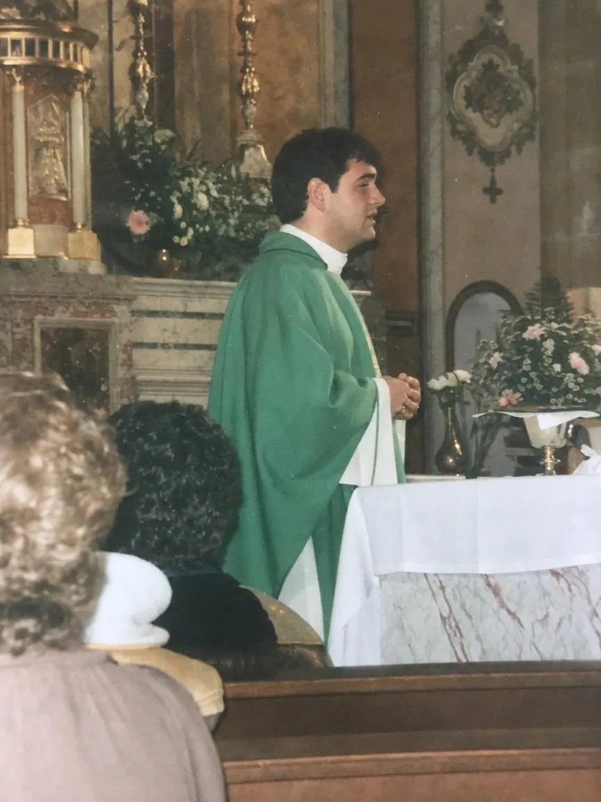 A young priest at the altar of a village church saying Mass