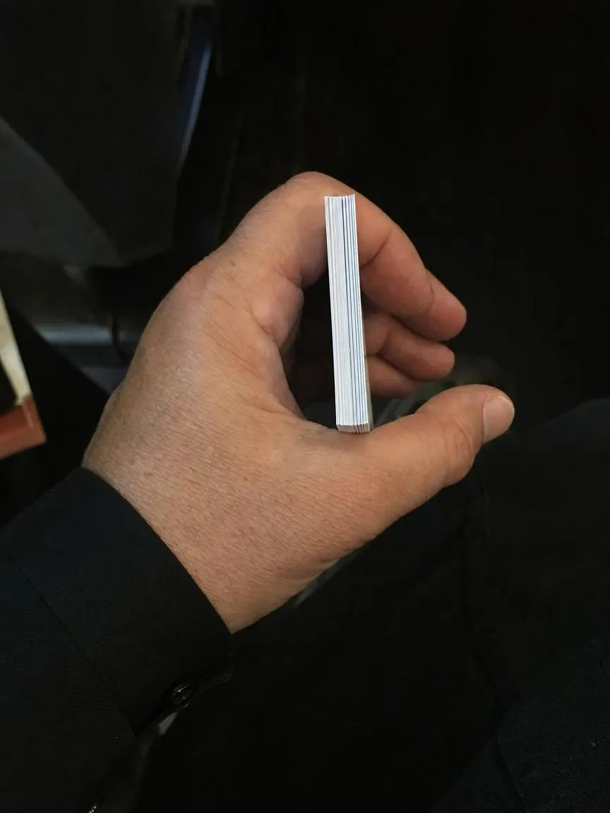 A hand holding a thick stack of printed prayer cards